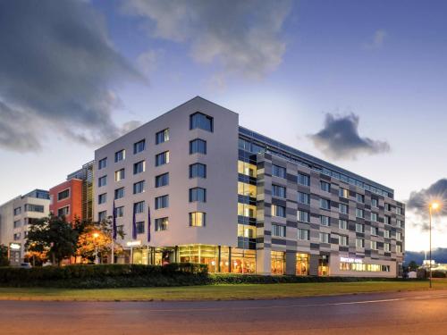 a large white building with windows on a street at Mercure Hotel Frankfurt Eschborn Helfmann-Park in Eschborn