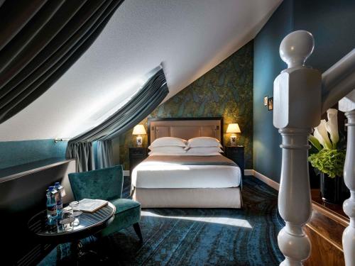 a bedroom with a bed and a green chair at Hotel Rotary Geneva - MGallery in Geneva