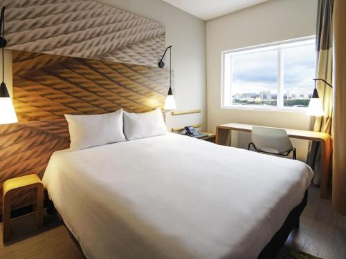 ein Hotelzimmer mit einem großen Bett und einem Fenster in der Unterkunft ibis Osasco in Osasco