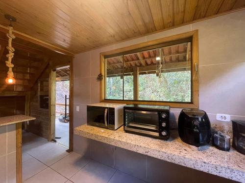 une cuisine avec un four micro-ondes sur un comptoir et une fenêtre dans l'établissement Casa das Pedras - Um recanto de paz em Santa Tereza, à Santa Teresa