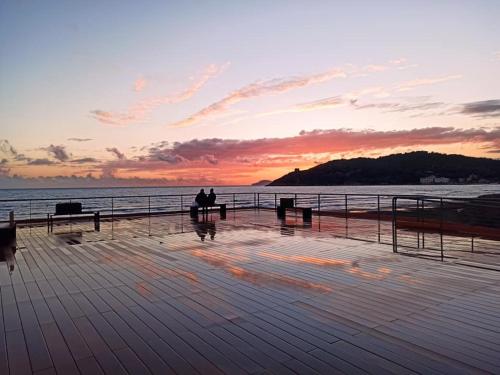 two people sitting on benches on a pier at sunset at La Colonnina in Minturno