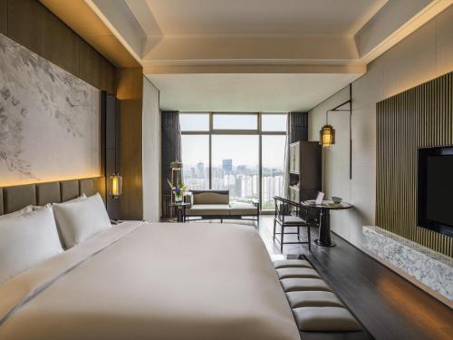 杭州市にあるSofitel Hangzhou Yingguan-Olympic Center Hotelの大きなベッドとテレビがあるホテルの部屋