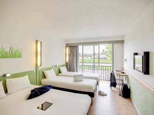 レスカーにあるibis budget Pau Lescarのベッド2台とバルコニー付きのホテルの部屋
