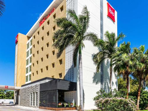 a hotel with palm trees in front of it at Ibis Merida in Mérida