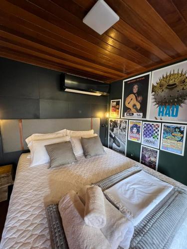 a bedroom with a large bed with pillows and posters at Casa Jasmim em Domingos Martins a 5km do Centro in Domingos Martins