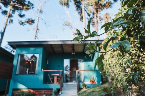 a blue tiny house with a porch in the woods at Chalé Climatizado com banheira em frente ao Parque do Passaúna em Curitiba by Tiny House Passaúna in Curitiba