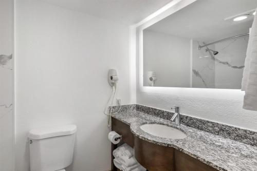 a bathroom with a sink and a mirror and a toilet at Best Western Palm Beach Lakes in West Palm Beach