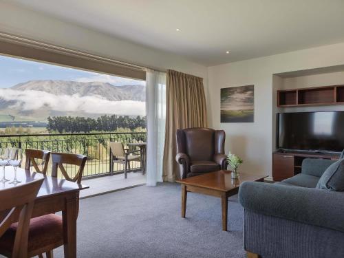 Una sala de estar con un sofá y un televisor y un balcón. en Fable Terrace Downs Resort by MGallery, en Windwhistle