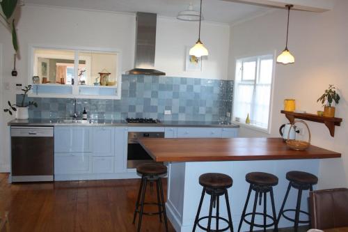a kitchen with white cabinets and a wooden island with bar stools at Hearth House - Character Family Home in Hastings