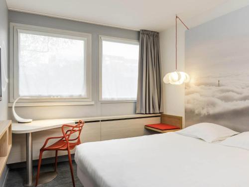 a bedroom with a bed and a desk and a window at ibis Styles Paris Velizy in Vélizy-Villacoublay
