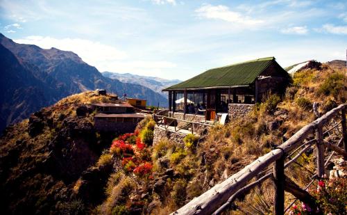 a building on the side of a mountain with flowers at La Granja del Colca in Cabanaconde