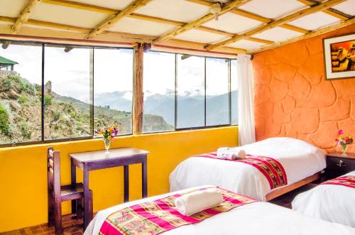 a room with two beds and a table and windows at La Granja del Colca in Cabanaconde