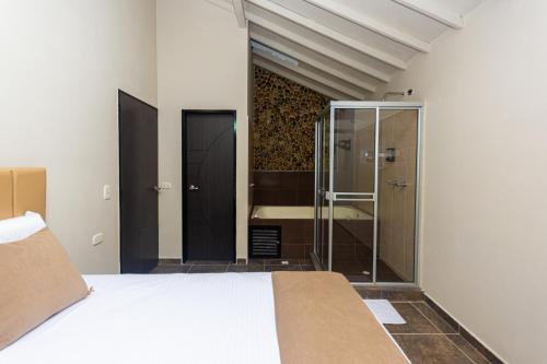 une chambre avec un lit et une douche en verre dans l'établissement Hotel Bossanova, à Rionegro