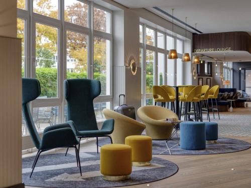 a room with chairs and tables and windows at Mercure Neu-Isenburg in Neu Isenburg