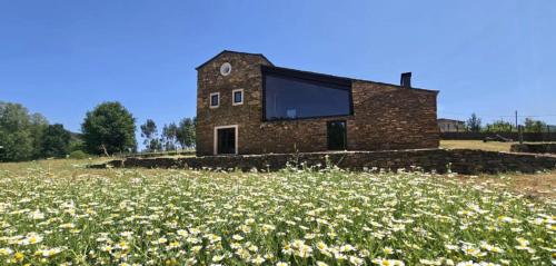 a brick house with a large window on a field of flowers at Linhares - Country House Turismo, Natureza e Aventura in Castanheira de Pêra