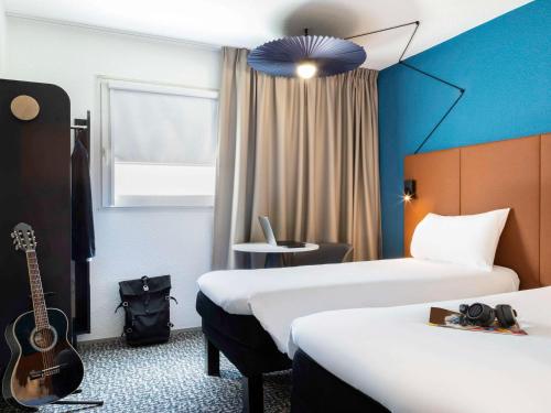 - une chambre d'hôtel avec 2 lits et une guitare dans l'établissement ibis Paris porte de Bercy, à Charenton-le-Pont