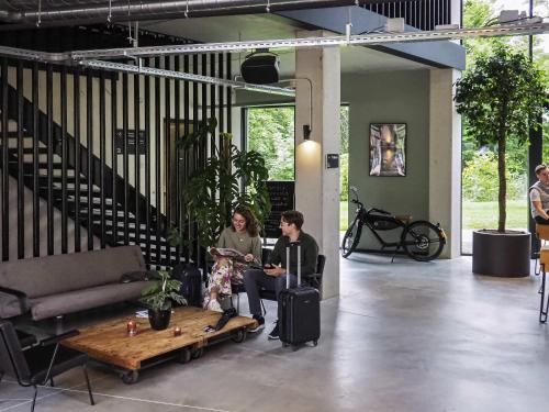two people sitting in a living room with a table at Hotel Valkenburg by Mercure - Next to Shimano Experience Center in Valkenburg