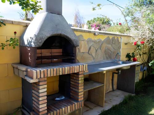 an outdoor pizza oven with a sink and a counter at Chalet con piscina privada solo familias y parejas in Roche