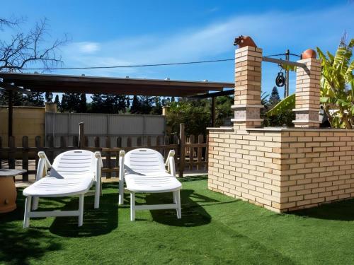 a couple of white chairs sitting on the grass at Chalet con piscina privada solo familias y parejas in Roche