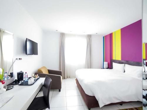 a hotel room with a white bed and a colorful wall at Ibis Styles Accra Airport in Accra