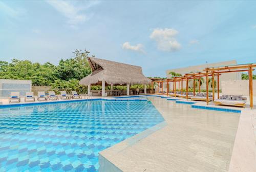a swimming pool with chairs and a straw umbrella at Exclusiva casa en Baru con piscina y playa privada in Playa Blanca