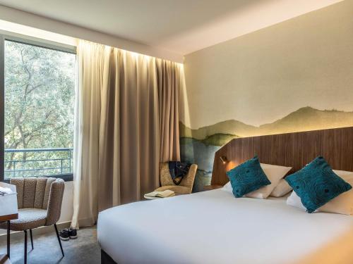 Una habitación de hotel con una cama y una ventana grande. en Mercure Aix-en-Provence La Duranne Gare TGV, en Aix-en-Provence