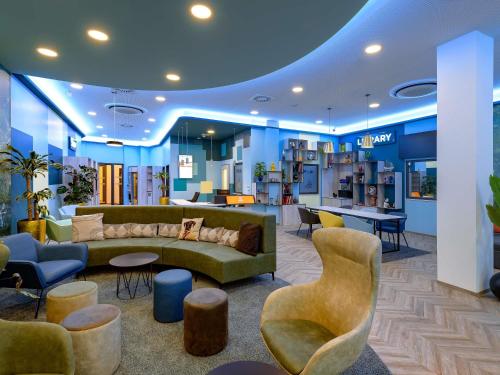 a lobby with a couch and tables and chairs at Aparthotel Adagio Access Kiel City in Kiel