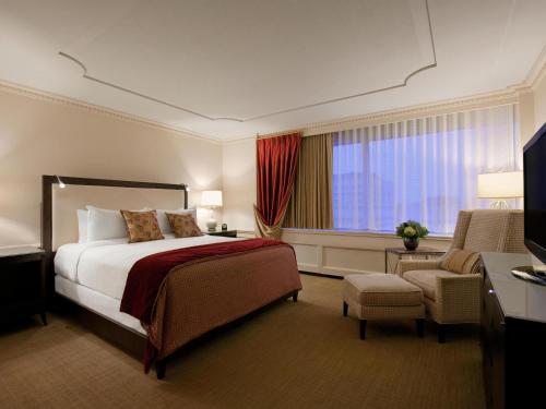 a hotel room with a bed and a chair at Fairmont Winnipeg in Winnipeg