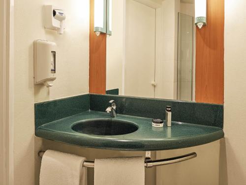 a bathroom with a green sink and a mirror at Ibis Monterrey Valle in Monterrey