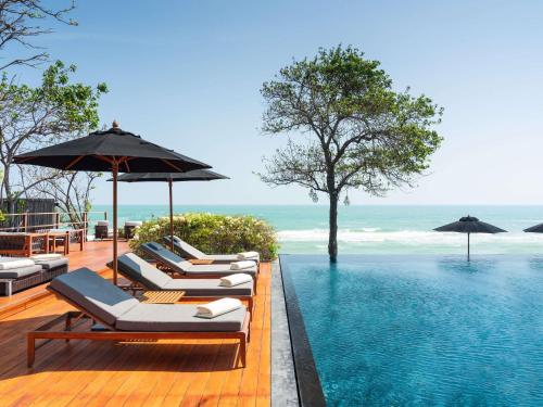 una fila de tumbonas junto a una piscina en V Villas Hua Hin - MGallery Collection, en Hua Hin