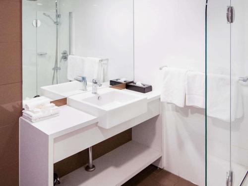 une salle de bain blanche avec un lavabo et une douche dans l'établissement ibis Styles Mt Isa Verona, à Mount Isa
