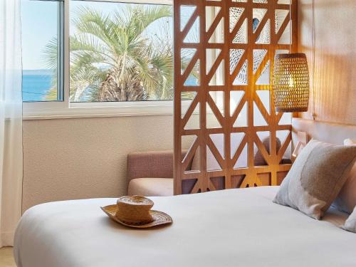 a bedroom with a bed with a hat on it at Mercure Saint Raphael Centre Plage in Saint-Raphaël
