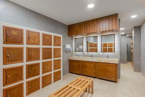 une grande salle de bain avec des armoires en bois et un banc dans l'établissement GR Solaris Cancun - All Inclusive, à Cancún