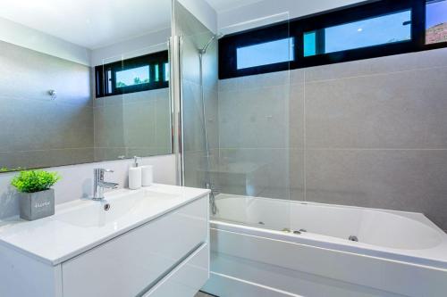 a white bathroom with a tub and a sink and a bath tubermott at Leonor Seaview Apartment in Funchal
