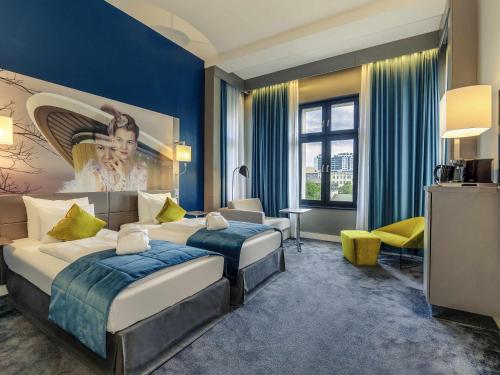a bedroom with two beds and a blue wall at MERCURE Hotel Berlin Wittenbergplatz in Berlin