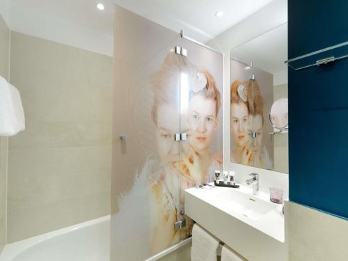 a bathroom with a large poster of two women on the wall at MERCURE Hotel Berlin Wittenbergplatz in Berlin