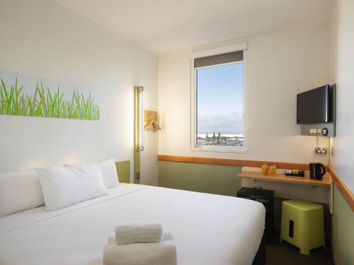 a bedroom with a large white bed and a window at ibis Budget Auckland Airport in Auckland