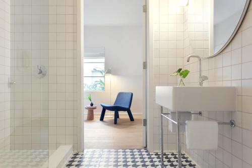 a bathroom with a sink and a blue chair at The Kimpton Shorebreak Fort Lauderdale Beach Resort in Fort Lauderdale