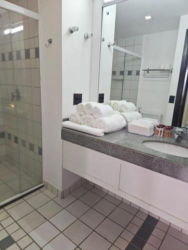 a bathroom with a sink and a mirror and towels at Prime Flat II - Metrópolis Alphaville in Barueri