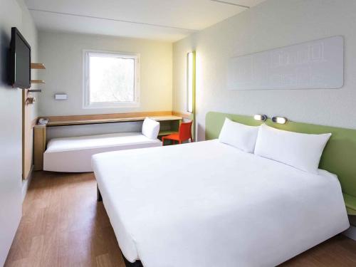 Una habitación de hotel con una gran cama blanca y un sofá. en Ibis Budget Madrid Alcorcón Móstoles, en Alcorcón