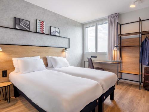 a hotel room with a large white bed and a desk at ibis Dijon Sud in Perrigny-lès-Dijon