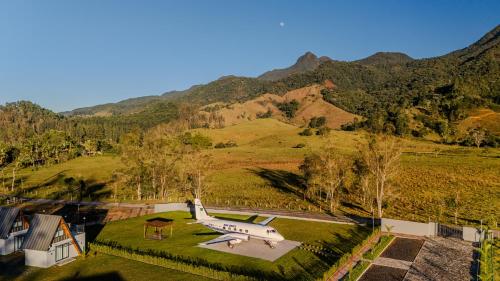 Ein Flugzeug ist auf einem Feld vor einem Berg geparkt. in der Unterkunft Pousada Aero Sofiste in Divino de São Lourenço