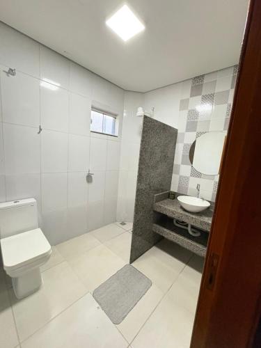 a white bathroom with a toilet and a sink at Casa Temporada Aconchego e tranquilidade 1 in Bonito