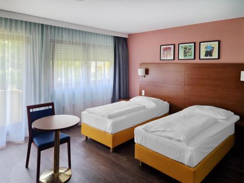 a hotel room with two beds and a table at Garner Hotel Stuttgart City Centre by IHG in Stuttgart