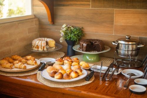 a table with different types of pastries and cakes at Chalés Estilo de Campos in Campos do Jordão
