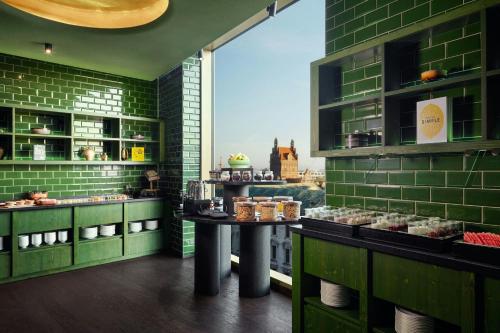 ミュンヘンにあるKoenigshof, a Luxury Collection Hotel, Munichの緑のレンガの壁とペストリーの置かれたテーブルのあるパン屋