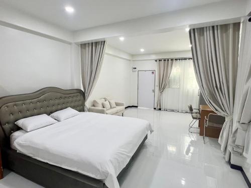 a bedroom with a large white bed and a chair at Diva house in Chiang Mai