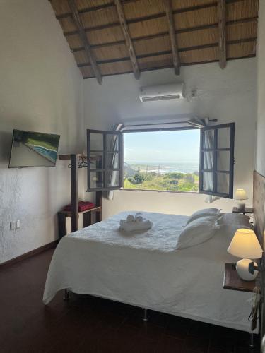 a bedroom with a large bed with a large window at cuatro lunas hotel in Punta Del Diablo