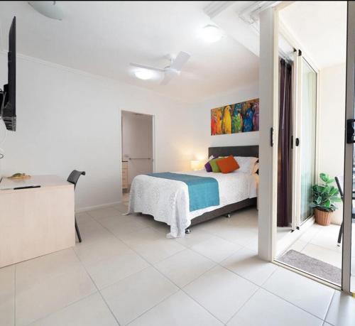 a white bedroom with a bed and a mirror at City Quays Accommodation 2 in Cairns