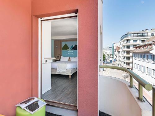 a bedroom with a view of a bed on a balcony at ibis Styles Annecy Centre Gare in Annecy